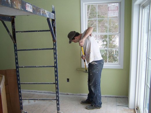 Pintor realizando trabalho com tinta em parede residencial. Pintor realizando trabalho com tinta em parede residencial